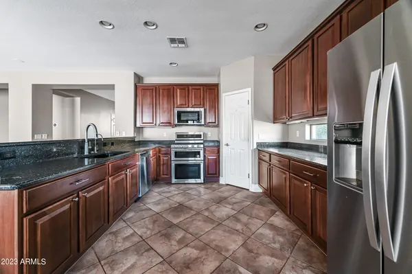 a large kitchen with stainless steel appliances granite countertop a stove refrigerator and a sink