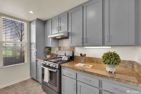 a kitchen with granite countertop a sink a stove and cabinets