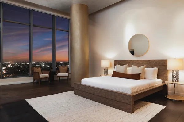 a bedroom with a bed lamps and a large window with wooden floor