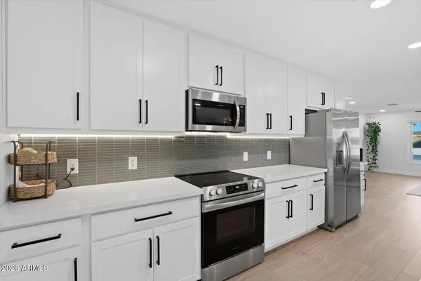 a kitchen with stainless steel appliances a stove a sink a kitchen island and chairs