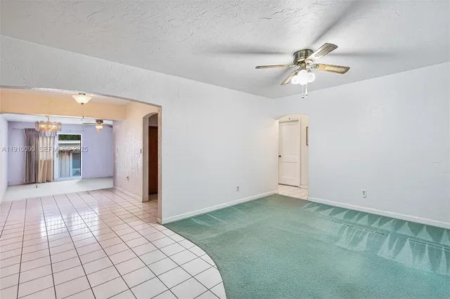 an empty room with chandelier fan and windows