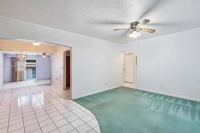 an empty room with chandelier fan and windows