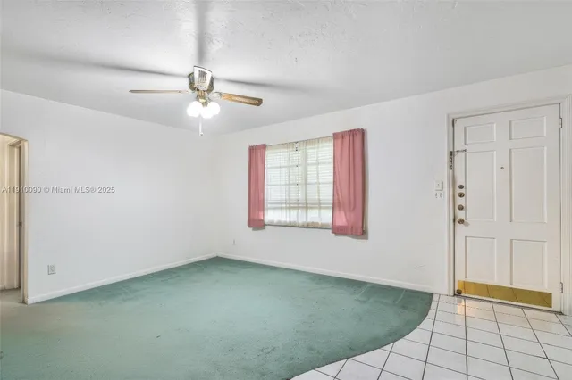 a view of an empty room with chandelier fan and a window