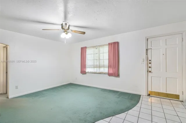 a view of an empty room with chandelier fan and a window