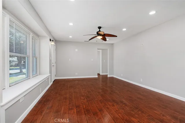 a view of an empty room with a window and wooden floor
