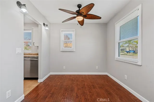 a view of empty room with wooden floor and fan