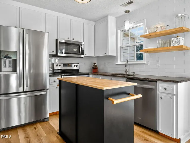a kitchen with stainless steel appliances granite countertop a refrigerator a sink and a stove