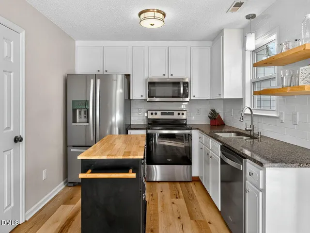 a kitchen with stainless steel appliances granite countertop a refrigerator a stove top oven a sink and dishwasher