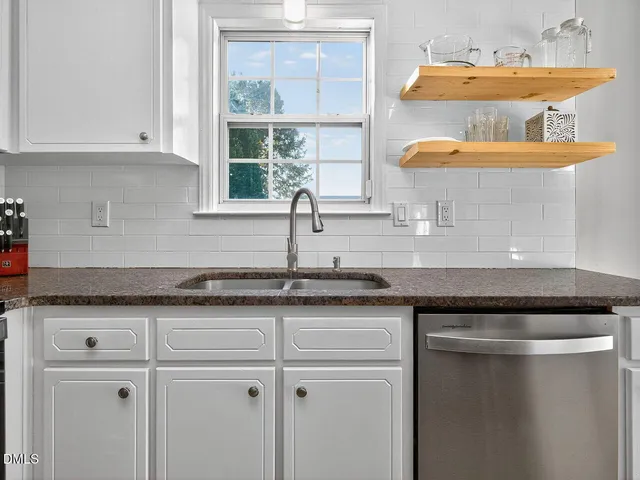 a kitchen with granite countertop a sink a window and cabinets
