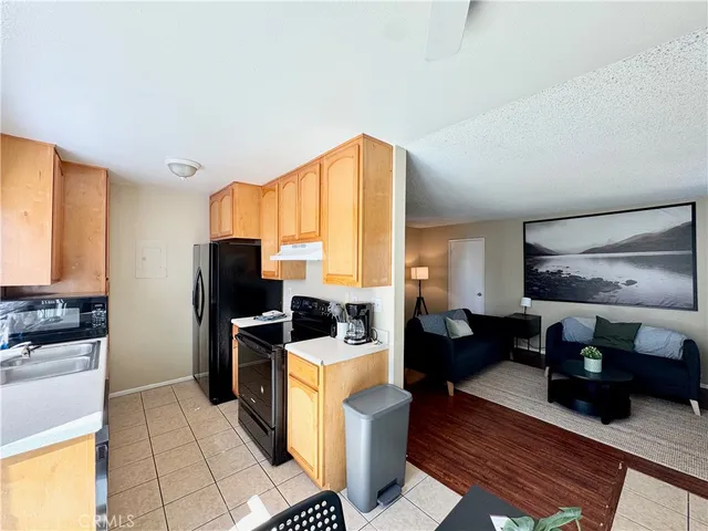 a living room with stainless steel appliances furniture a rug and a view of kitchen