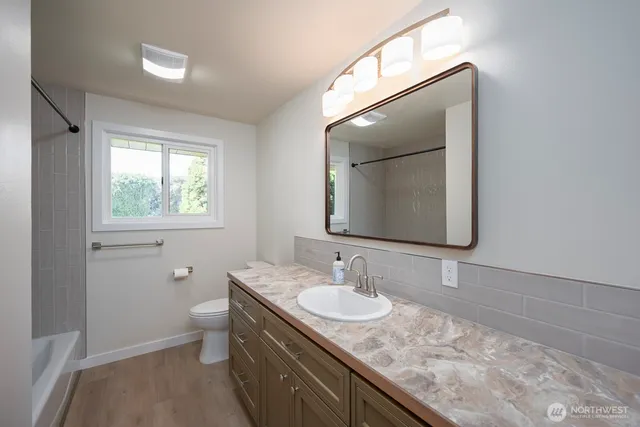 a bathroom with a granite countertop sink a toilet and mirror