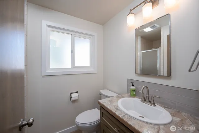 a bathroom with a granite countertop toilet a sink and mirror