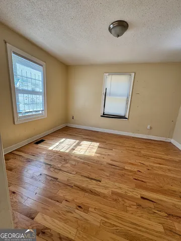 a view of an empty room with wooden floor and a window