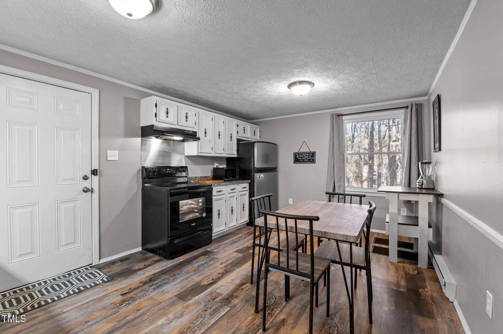 749 Fred Royster Road Henderson, NC 27537 - Photo 7 of 31 a kitchen with granite countertop a refrigerator a stove a dining table and chairs with wooden floor
