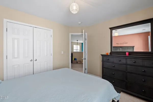 a bedroom with a bed and a mirror on dresser
