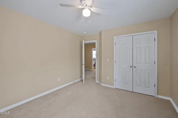 an empty room with closet and a ceiling fan