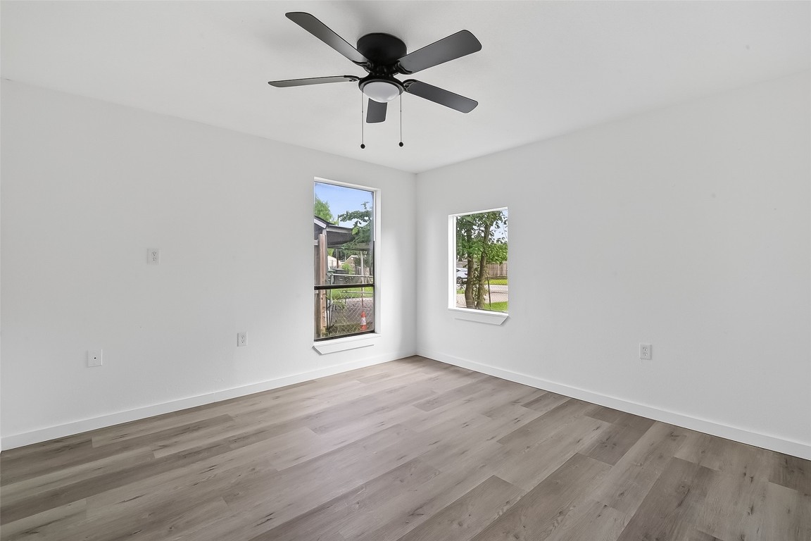 4933 Doolittle Boulevard Houston, TX 77033 - Photo 16 of 28 an empty room with wooden floor chandelier fan and windows