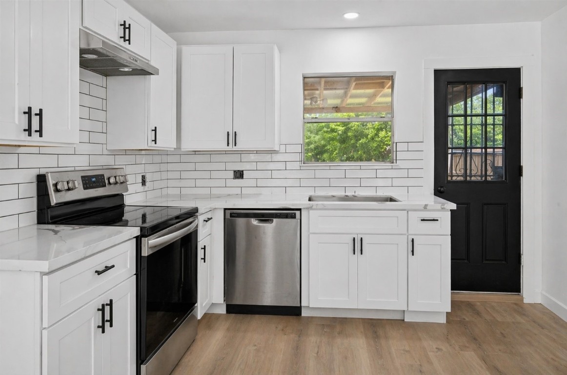 4933 Doolittle Boulevard Houston, TX 77033 - Photo 10 of 28 a kitchen with granite countertop white cabinets appliances a sink and a window
