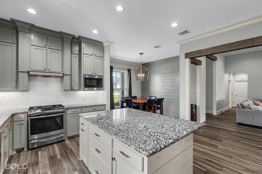 143 Oak Alley Road Stonewall, LA 71078 - Photo 18 of 38 Kitchen featuring a large island with a granite countertop, gray cabinetry, stainless steel appliances, and wood-finish flooring