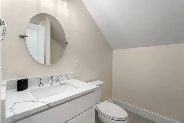 a bathroom with a granite countertop sink mirror vanity and toilet