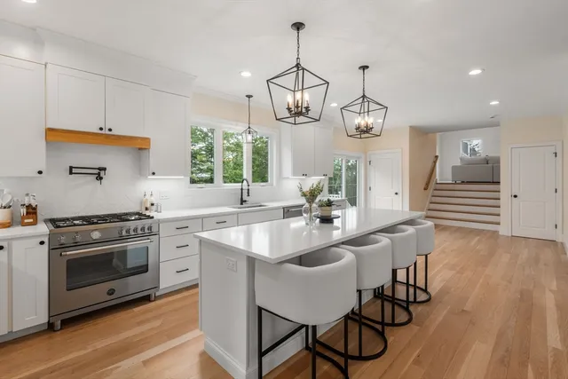 a kitchen with stainless steel appliances granite countertop a stove a sink dishwasher a dining table and chairs with wooden floor