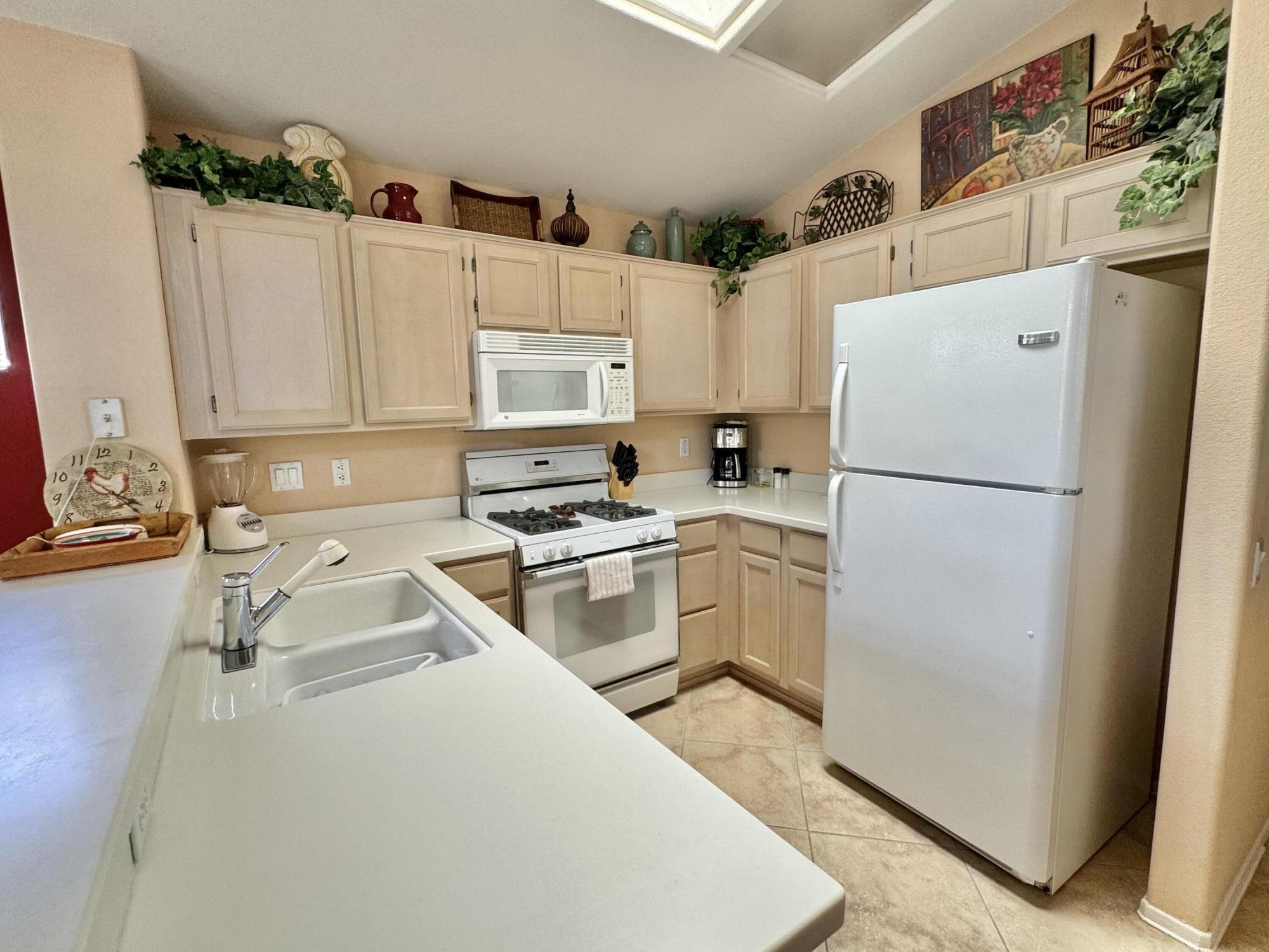78376 Moongold Road Palm Desert, CA 92211 - Photo 6 of 36 a kitchen with a refrigerator sink and white cabinets
