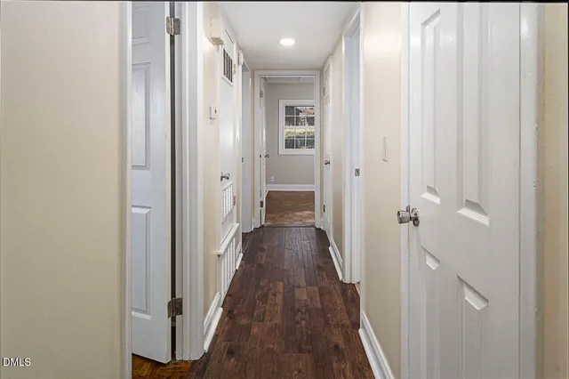 a view of a hallway with wooden floor and a bathroom