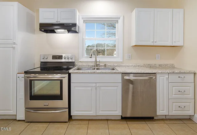 a kitchen with granite countertop white cabinets sink and white appliances