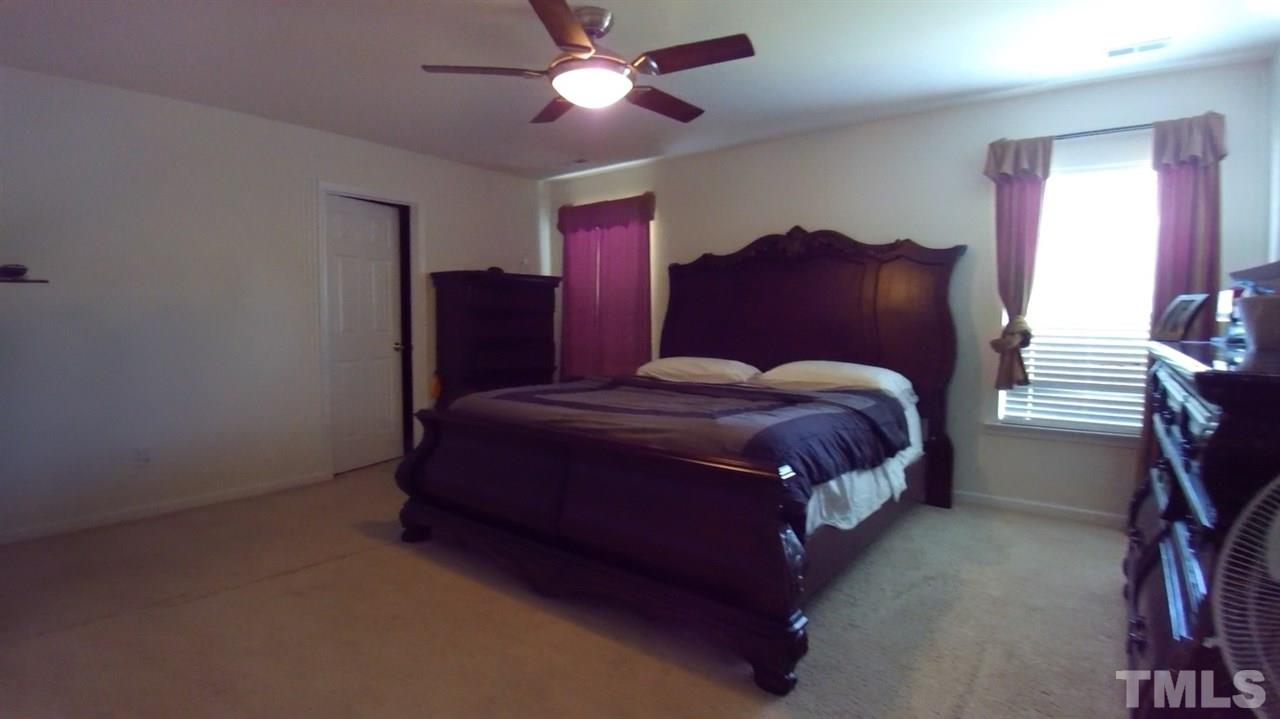 4028 Oatgrass Lane Raleigh, NC 27604 - Photo 7 of 8 a bedroom with a bed chandelier and a window