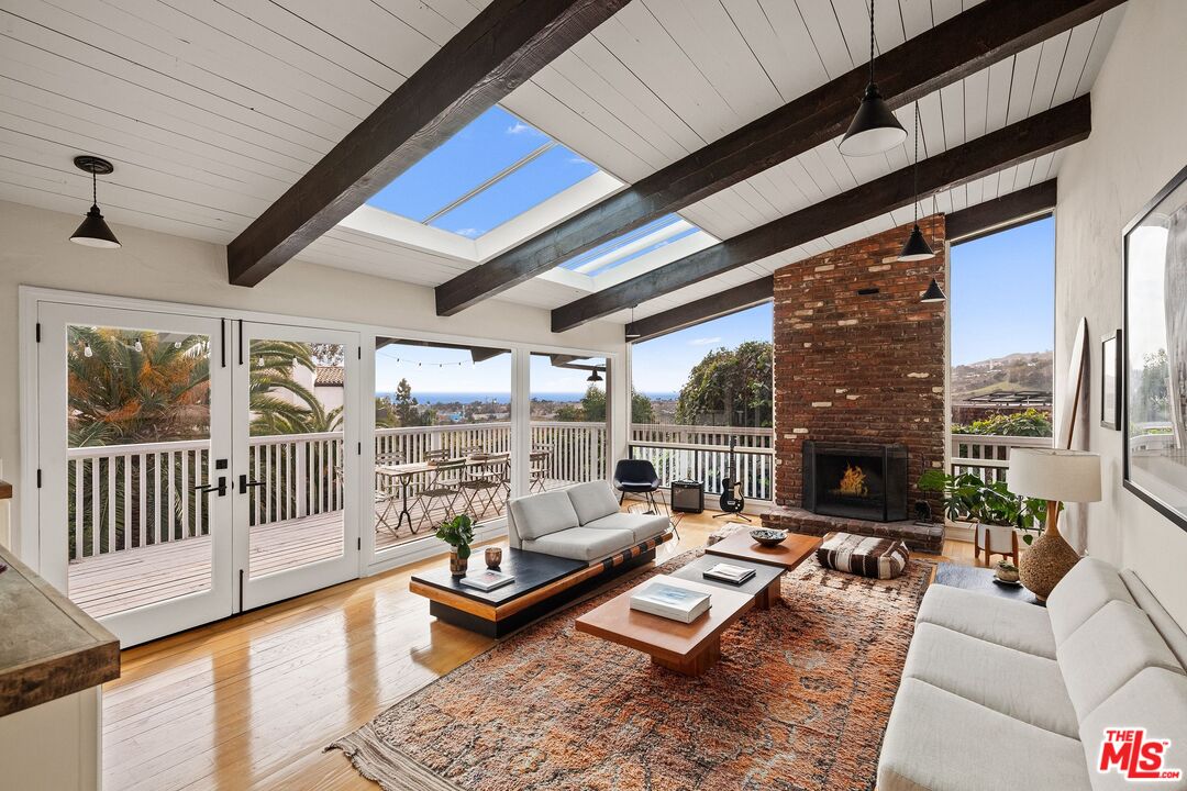 3629 Serra Road Malibu, CA 90265 - Photo 3 of 26 a living room with furniture a fireplace and a table