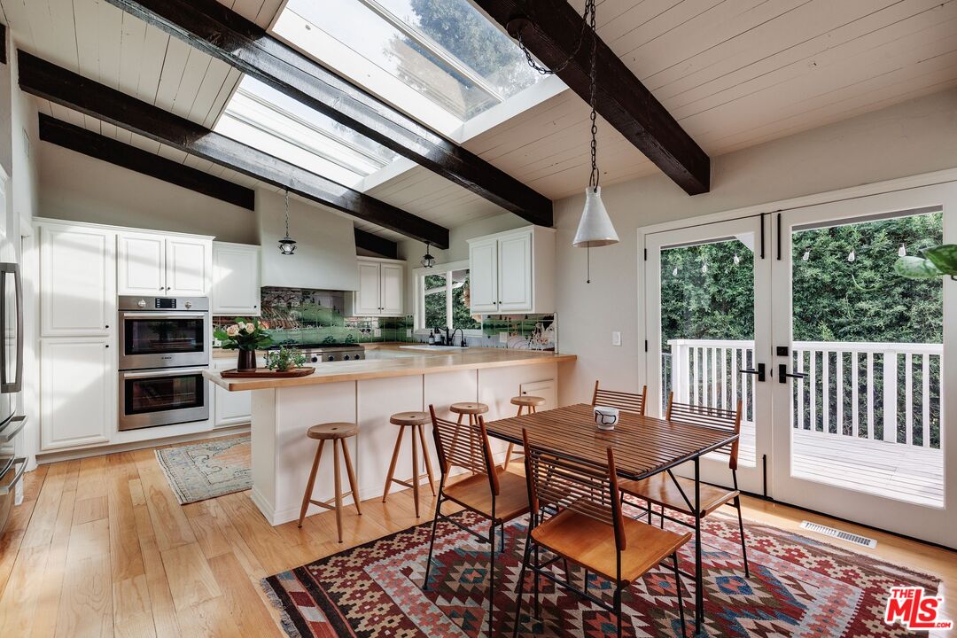 3629 Serra Road Malibu, CA 90265 - Photo 8 of 26 a kitchen with stainless steel appliances granite countertop a stove top oven a sink dishwasher a dining table and chairs with wooden floor
