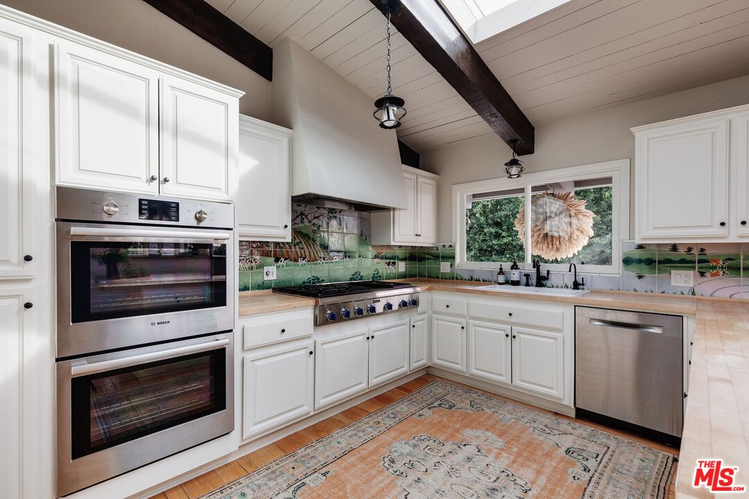 3629 Serra Road Malibu, CA 90265 - Photo 9 of 26 a kitchen with cabinets wooden floor and stainless steel appliances
