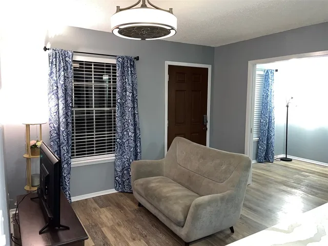 a living room with furniture a flat screen tv and a wooden floor