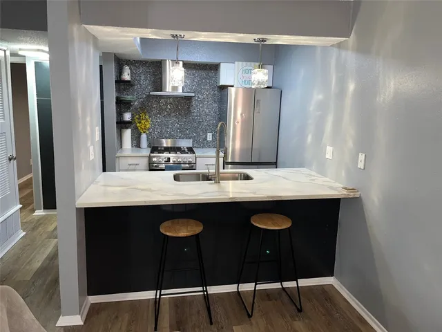 a kitchen with stainless steel appliances granite countertop a sink a stove a refrigerator and island