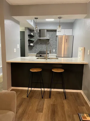 a kitchen with stainless steel appliances a dining table chairs and wooden floor