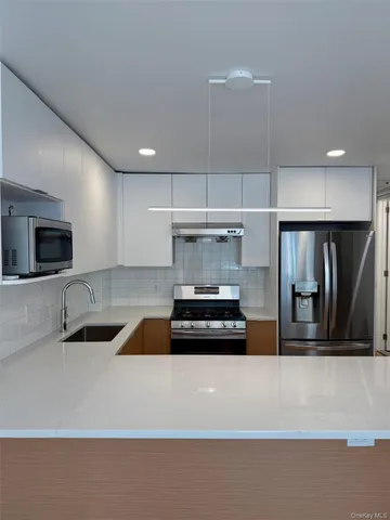 a kitchen with a refrigerator a sink and white cabinets