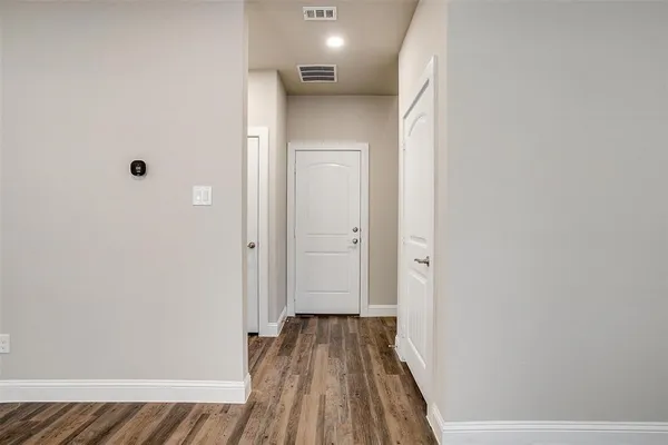 a view of a hallway with wooden floor and a bathroom
