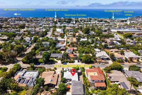 an aerial view of a city with lots of residential buildings ocean and mountain view in back