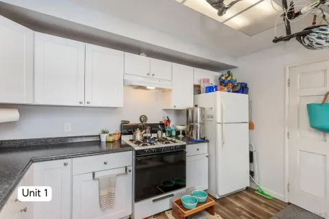 a kitchen with stainless steel appliances granite countertop a stove a refrigerator a sink a dining table and chairs with wooden floor