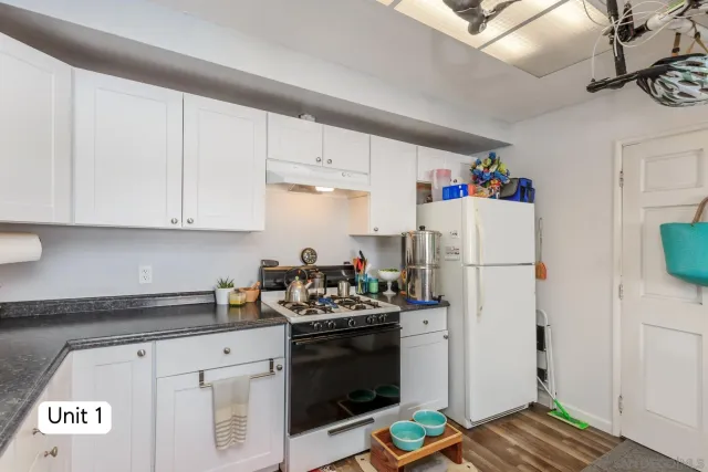 a kitchen with stainless steel appliances granite countertop a stove a refrigerator a sink a dining table and chairs with wooden floor