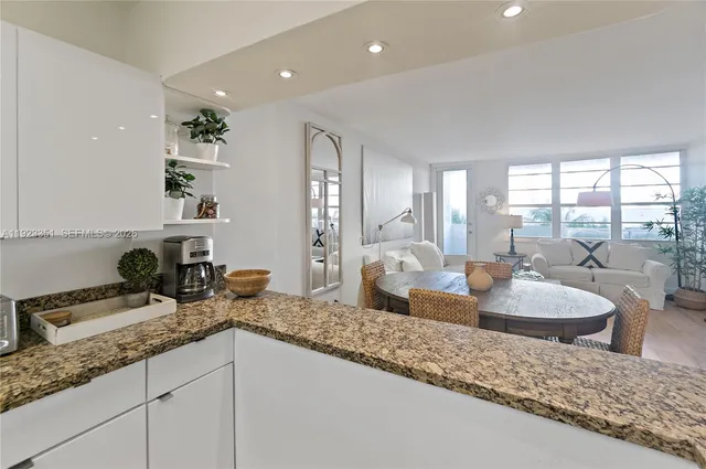 a kitchen with granite countertop a sink and a white wooden cabinets