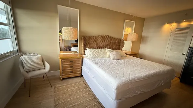 a bedroom with a bed and chair with mirror