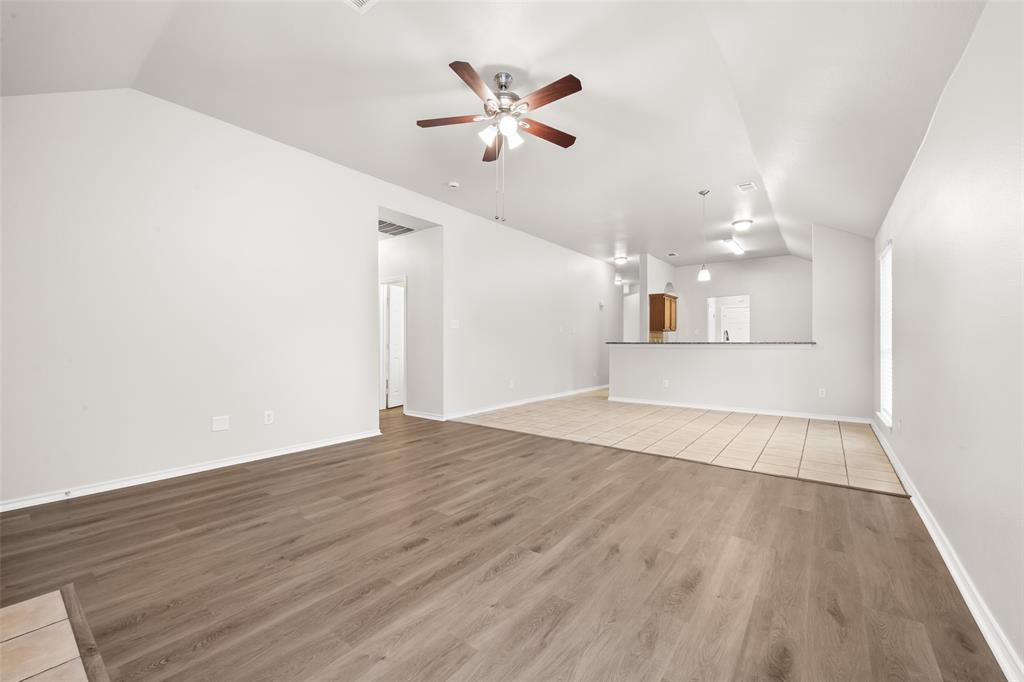 7928 Hill Country Lane Dallas, TX 75249 - Photo 9 of 19 an empty room with wooden floor and ceiling fan