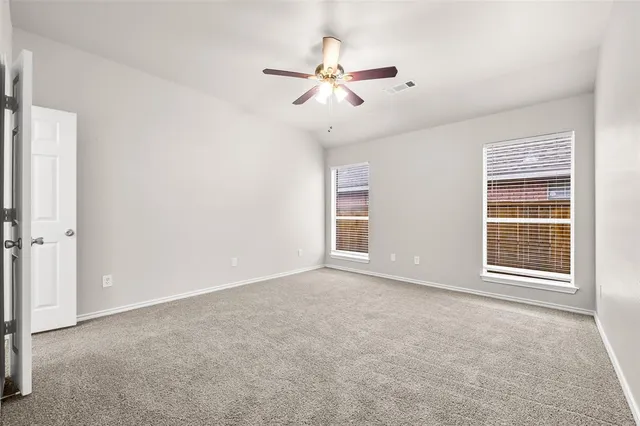an empty room with windows and fan