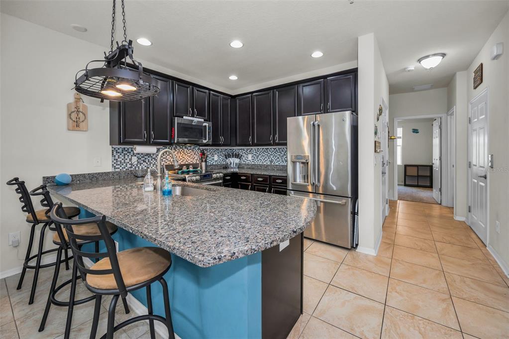 5529 White Marlin Court New Port Richey, FL 34652 - Photo 24 of 63 a kitchen with stainless steel appliances granite countertop a table chairs sink and refrigerator