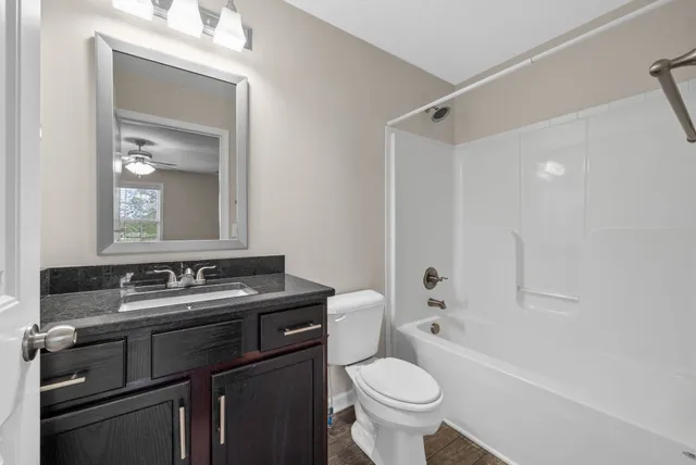 a bathroom with a granite countertop sink toilet and shower