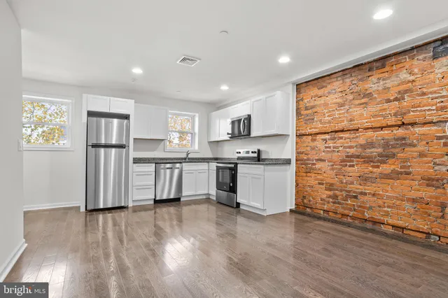 a kitchen with stainless steel appliances wooden floor and window