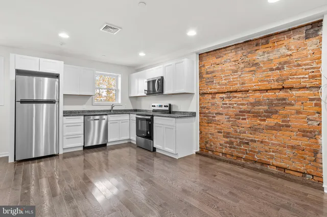 a kitchen with granite countertop a sink cabinets and stainless steel appliances