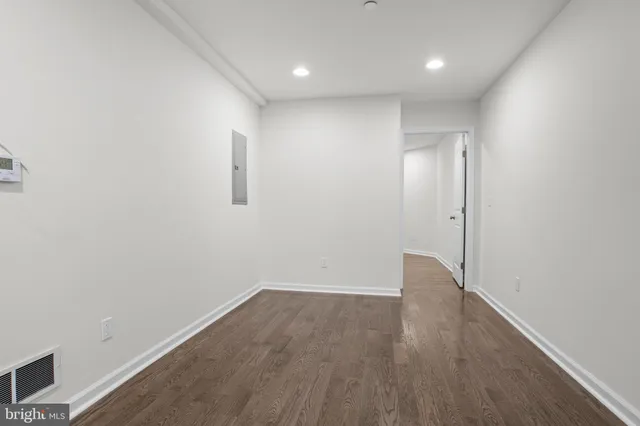 an empty room with wooden floor and bathroom