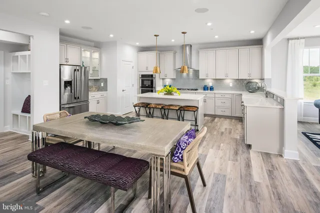 a open kitchen with stainless steel appliances granite countertop a dining table chairs refrigerator sink and microwave